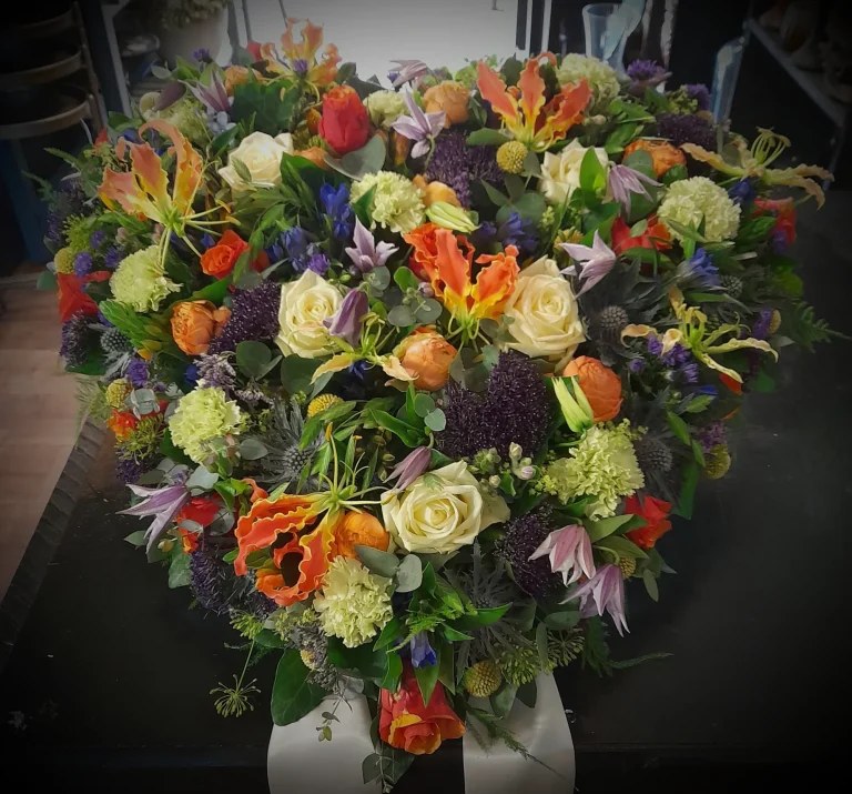 Kleurrijk rouwstuk met rozen, gloriosa en clematis – Bloem en Atelier Floriante