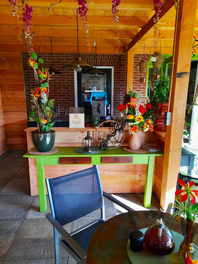 Koffiecorner met groene tafel en bloemen op het terras – Bloem en Atelier Floriante